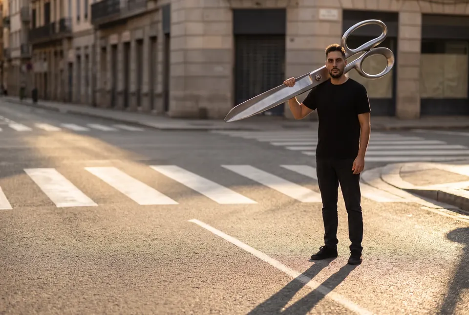 Richy in strada con un paio di forbici giganti in spalla